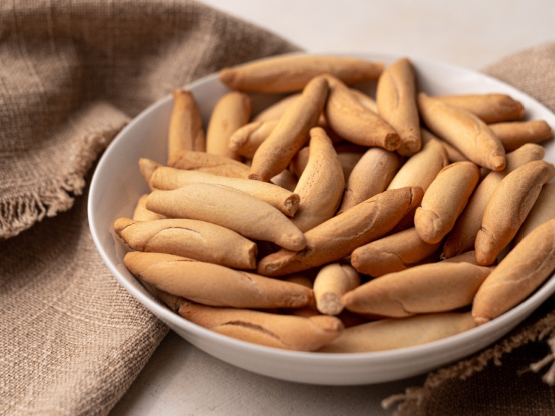 A Bowl of Breadsticks on a Table with Burlap