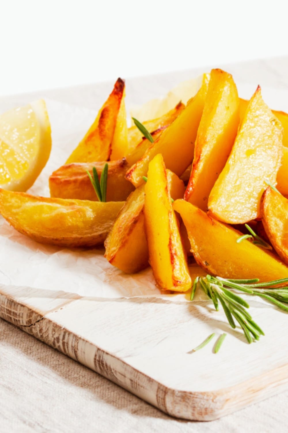 Baked Greek Lemon Potatoes Garnished With Herbs on a Cutting Board