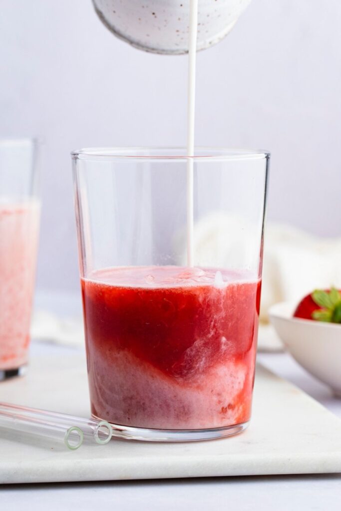 Pouring Cream on a Glass of Strawberry Juice