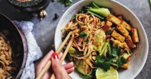 Woman Holding Chopsticks of Tofu Pad Thai